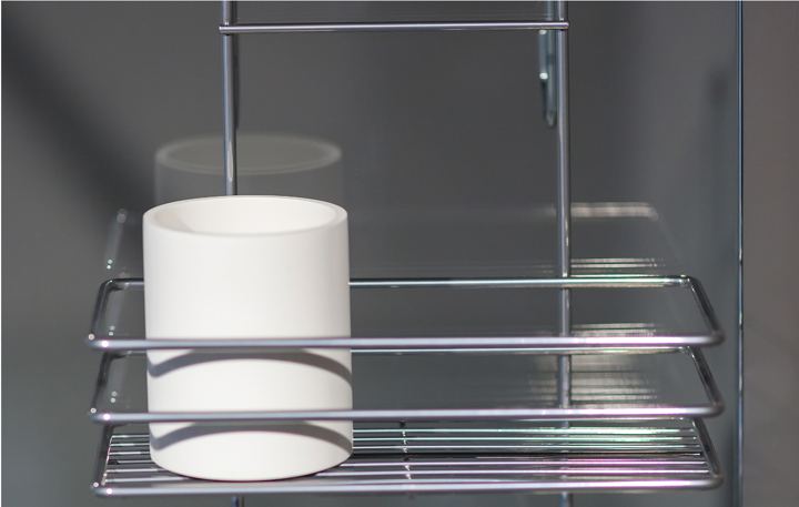 Close-up of a chrome shelf with a white cup