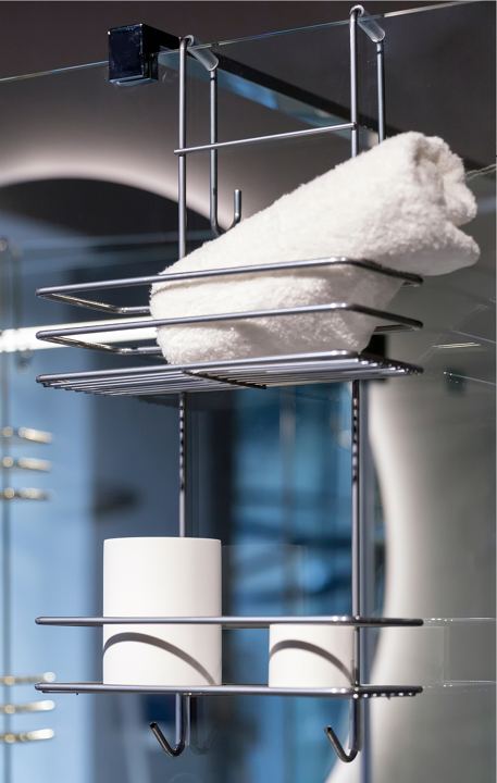 Chrome shelf on a glass shower door holding a rolled towel